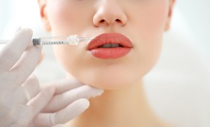 Closeup of crop anonymous female patient getting filler injection in lips in cosmetology clinic