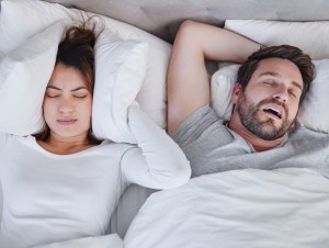 Shot of a young woman struggling to sleep with her boyfriend's snoring at home