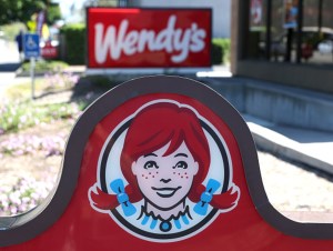 A sign is posted in front of a Wendy's restaurant