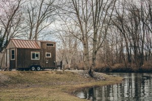 A tiny home and tree reflection in a pond on a cloudy day.