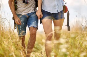 Close up shot of couple hiking in field, holding hands. Nature outdoors. Caucasian couple. Sport, freedom, holiday concept.