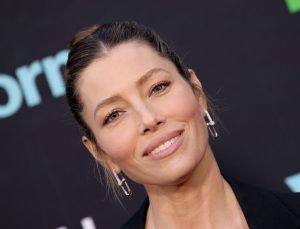 Jessica Biel attends the premiere of Freeform's "Cruel Summer" Season 2 smiling wearing a black top hair pulled back and dangly earrings.