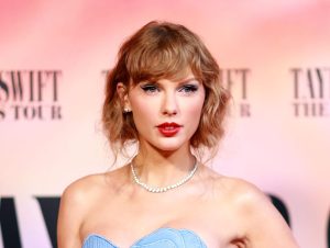 Taylor Swift attends "Taylor Swift: The Eras Tour" Concert Movie World Premiere with bangs and a strapless baby blue dress and pearl necklace.