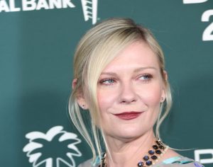 Kirsten Dunst attends the 2023 Baby2Baby Gala smiling looking right wearing a teal dress and dark pearl necklace.
