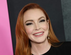 Lindsay Lohan attends the "Mean Girls" premiere at AMC Lincoln Square smiling with red hair and wearing a black top.