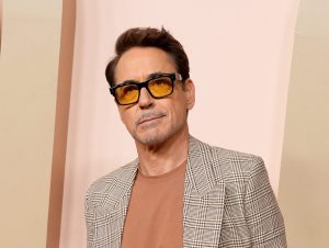 Robert Downey Jr. attends the 96th Oscars Nominees Luncheon wearing a light grey suit and brown undershirt, Robert Downey Jr. Jokes He’s A 'Fledging Interior Designer'.