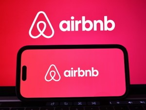 In this photo illustration, the Airbnb logo is displayed on a computer monitor and cell phone