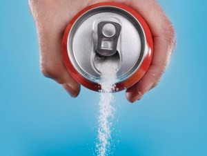 hand holding soda can pouring a crazy amount of sugar in metaphor of sugar content of a refresh drink isolated on blue background in healthy nutrition, diet and sweet addiction, unhealthiest drinks concept