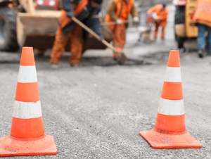 road workers repairing the road with shovels, dub asphalt with shovels at the back, the cones in the foreground