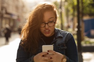 Angry woman using cellphone outdoors.
