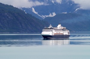 A cruise ship sailing the seas in front of snow-covered mountains.