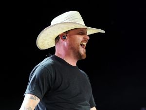 Cody Johnson Revealed A Tattoo - Cody on stage in a black t-shirt and cowboy hat.