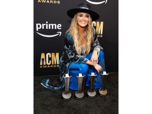 Lainey Wilson's 2024 ACM Nominations—Lainey poses with her four ACM Awards, wearing a blue and black outfit with a black hat, after the show in 2023.