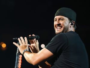 Luke Bryan Says Having Beyonce In Country -Luke is on stage wearing a black shirt and ball cap, smiling.