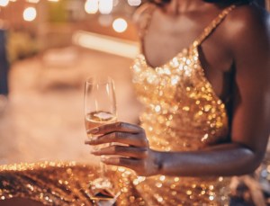 Close-up of beautiful young African woman in evening gown holding flute with champagne while spending time on night party