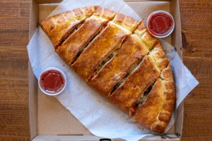 A cut calzone with sides a tomato sauce. The best calzone in Massachusetts is at McGoo's in south Boston.