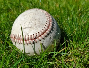 White old baseball ball on fresh green grass with copy space closeup.