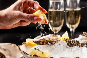 Prosecco bar concept. Open oysters lie on crushed ice with lemon and lime, next to a glass of champagne. Pennsylvania Seafood