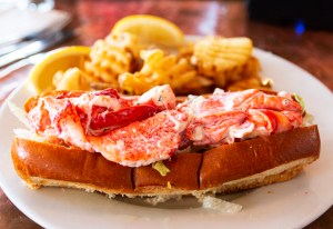 A fresh lobster roll served with waffle fries in a New England seafood restaurant