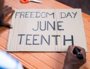 Shoulder shot of activist preparing freedom day junteenth sign board for marching