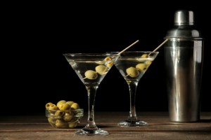 Martini in a glass wineglass with green olives on a skewer on a brown wooden table. North Carolina restaurant