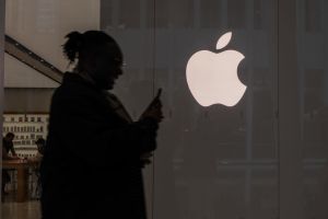Apple logo and person on a phone. Is the new iPhone update resurrecting deleted nudes?