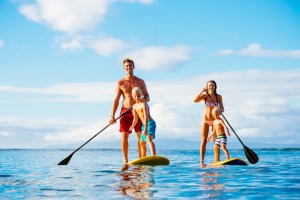 Family Having Fun Stand Up Paddling Together in the Ocean on Beautiful Sunny Morning. New England hotel