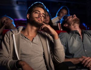 Young people watching a boring movie at the cinema, one guy is sleeping