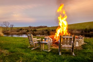 Bonfire in a firepit at sunset. North Carolina vintage trailer hotel summer evening.