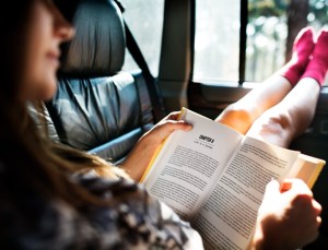 Girl Reading Book Inside Car road trip Concept