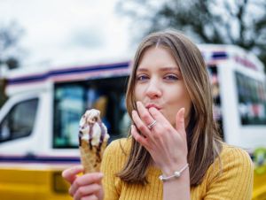 Young woman eating ice cream infront of ice cream truck