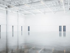 Corner of modern empty warehouse with white walls, concrete floor and black doors. Concept of storage. 3d rendering