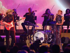 Chris Staple in black and Dua Lipa in a blue dress perform at the 2024 ACM Awards.