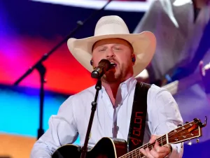 Cody Johnson performing in a white shirt and cowboy hat.