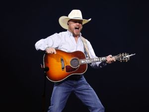 Cody Johnson on stage in a white shirt and cowboy hat.