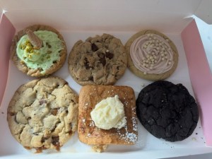 An array of Crumbl cookie special flavors in a pink box on a table