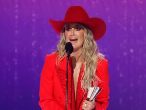 Lainey Wilson in red accepting a 2024 ACM Awards.