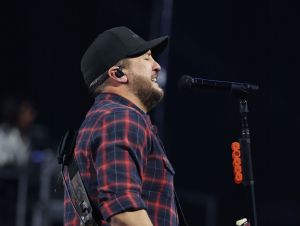 Luke Bryan is on stage in red plaid.
