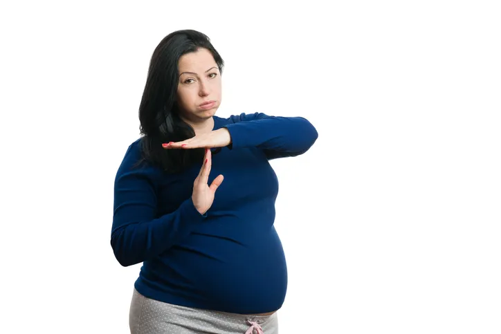 Pregnant woman making time-out gesture isolated on white background as eight months pregnancy concept