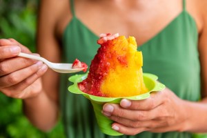 A woman eating shave ice in a green dress in Honolulu Waikiki. Best shave ice in Fayetteville
