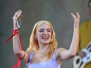 Lorde performs on the Pyramid Stage during day five of Glastonbury Festival smiling with her arms raised up wearing a lilac leotard and long blond hair. Lorde Teases New Album With Spit.