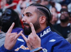 Drake attends a game between the Houston Rockets and the Cleveland Cavaliers at Toyota Center looking to the left, throwing up rock-star hand signs, Drake Seemingly Shades Kendrick After Calling Himself The 'GOAT'.