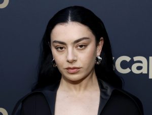 Charli XCX attends the 2024 ASCAP Pop Music Awards wearing a black plunging dress, black hair parted in the middle and small hoop earrings, Charli XCX’s ‘Brat’ Album Highly Rated By Fans And Critics.