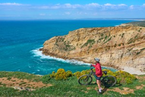 woman cycling with her mountain bike on the cliffs during an outdoor adventure tours