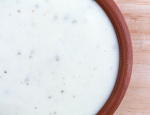 Top close view of a small bowl of ranch dressing on a wood table top illuminated with natural light.