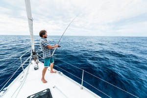 Young man fishing in open sea from sail boat on fishing excursions in Massachusetts