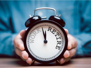 Businessman holding black alarm clock with clockwise countdown from work to retirement.