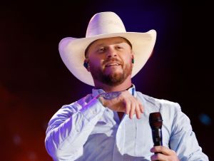 Cody Johnson in a blue shirt and cowboy hat performing at CMA Fest 2024.