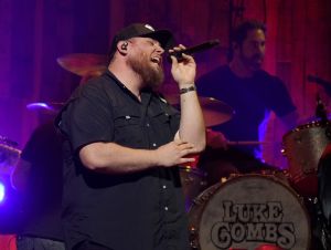 Luke Combs is performing on stage wearing a black shirt.