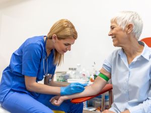 Woman taking blood of a patient.